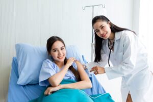 Asian young female doctor with syringe to the arm of Asian young